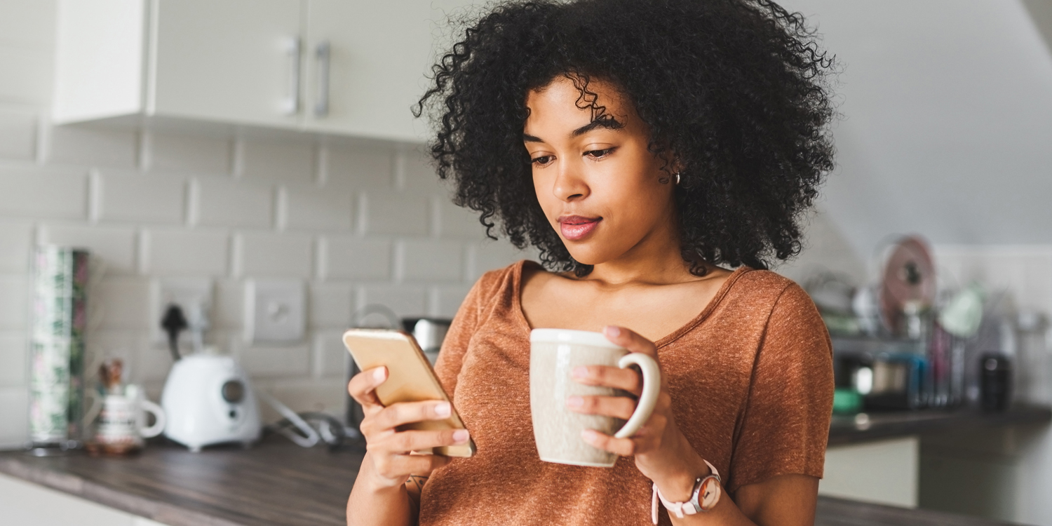 woman drinking coffee and looking at her phone