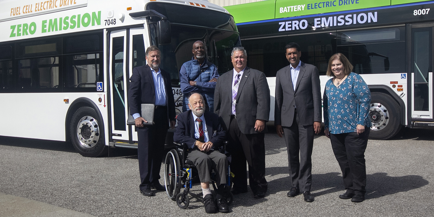 Board of Directors, General Manager Michael Hursh, and Rep. Ro Khanna standing for a posed picture in front of two zero emission buses