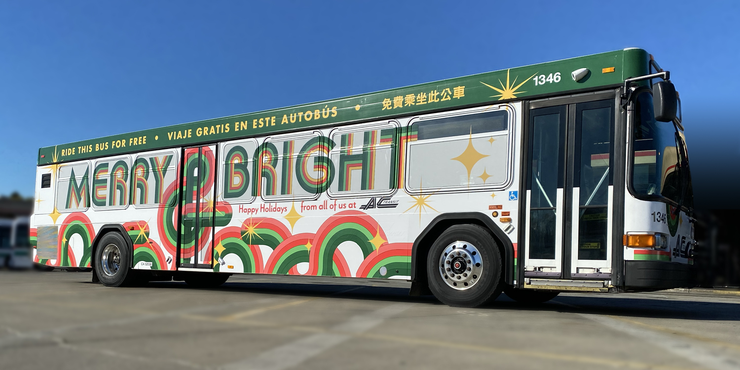 Holiday bus parked in bus yard with wrap reading "Merry & Bright"