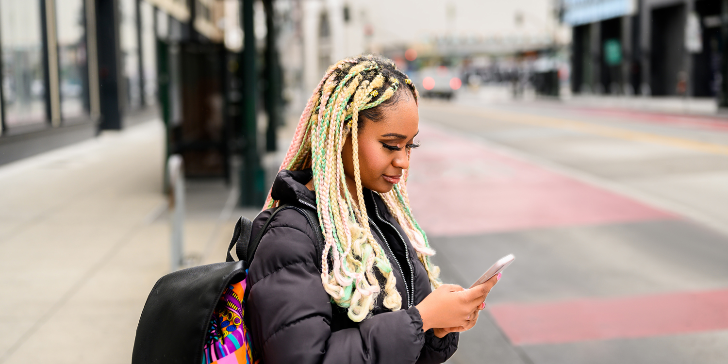 Woman at the bus stop, looking at her phone
