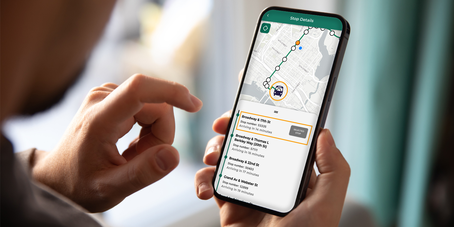 Holding a smart phone with the AC Transit Mobile App open on screen