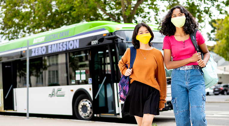 Two women walking away from AC Transit bus