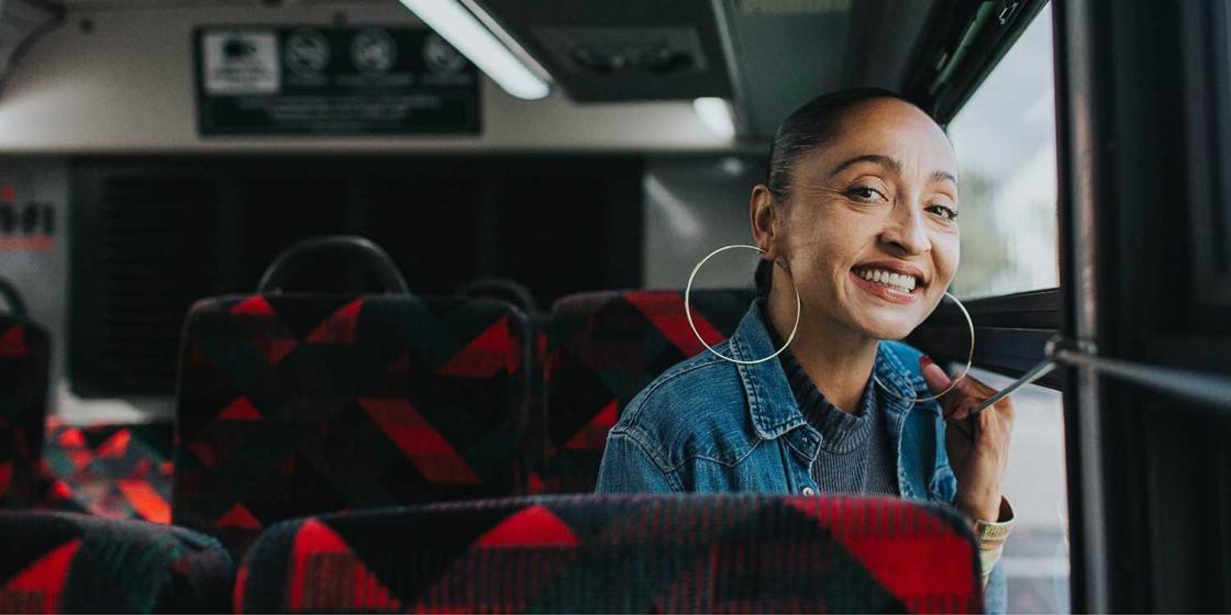Woman sitting on bus, smiling at camera