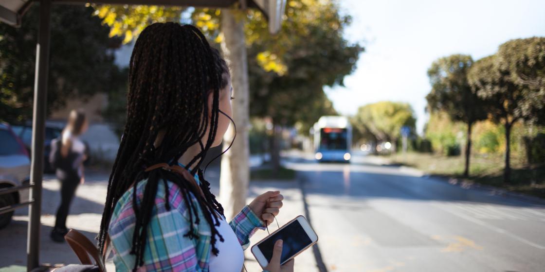 Woman holding phone, waiting for bus