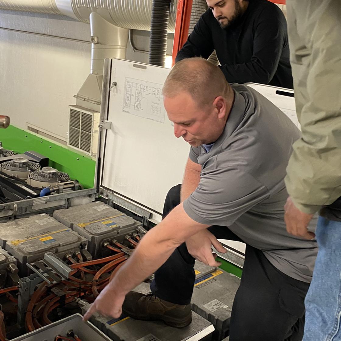 AC Transit mechanic displaying engine to students