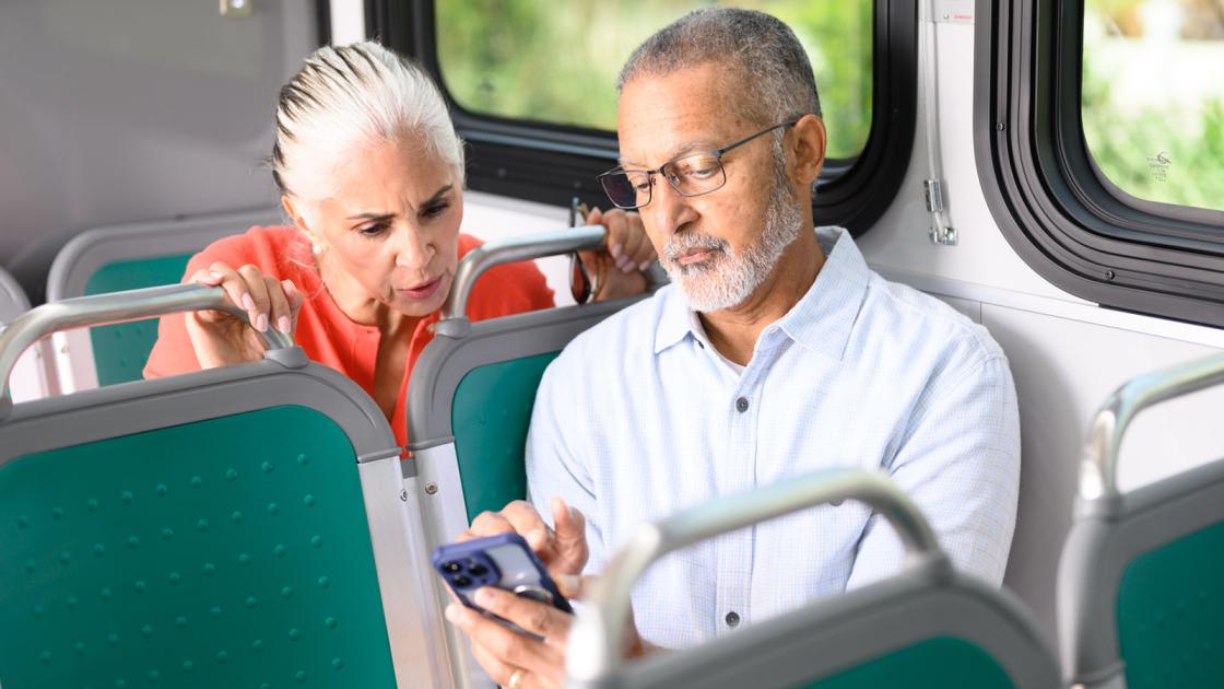 Man and woman checking phone on AC Transit bus