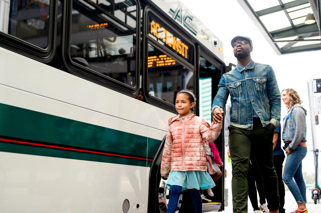 Man walking with daughter outside of AC Transit bus