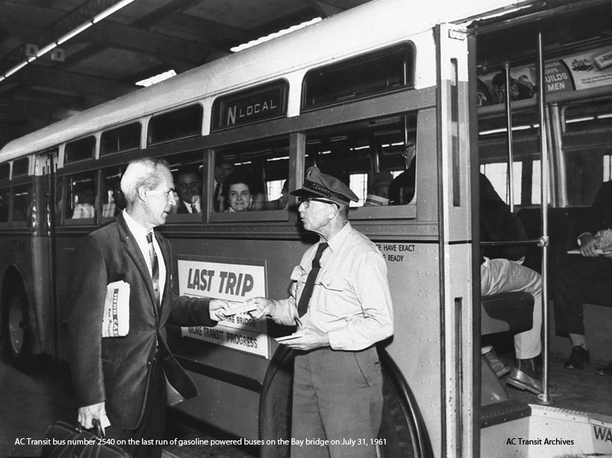 AC Transit driver James Oates gives a commuter one of the souvenir cards commemorating the last trip of a gasoline-powered bus on the Bay Bridge.  The bus is number 2540.